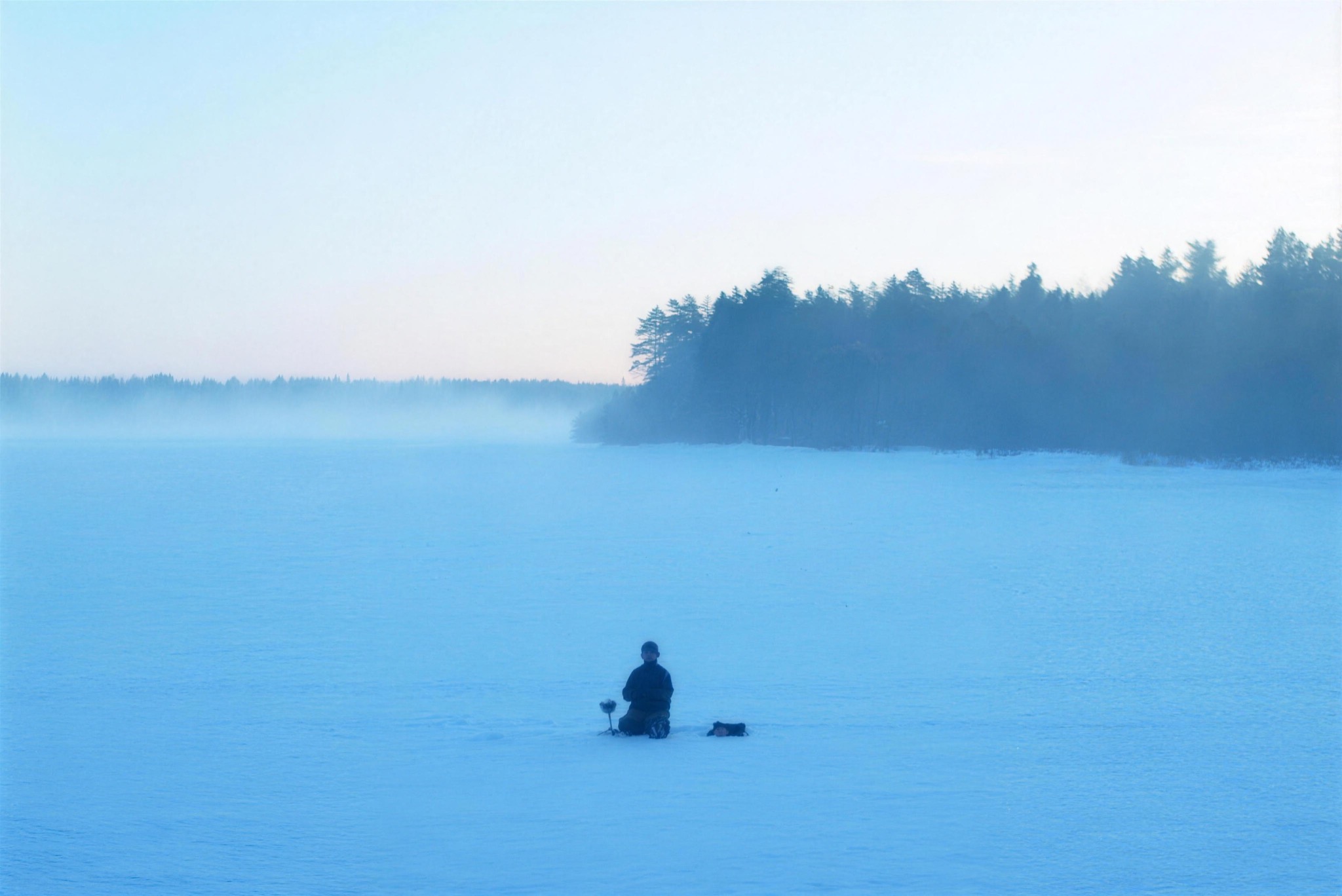 An ice fisher on a vast frozen lake