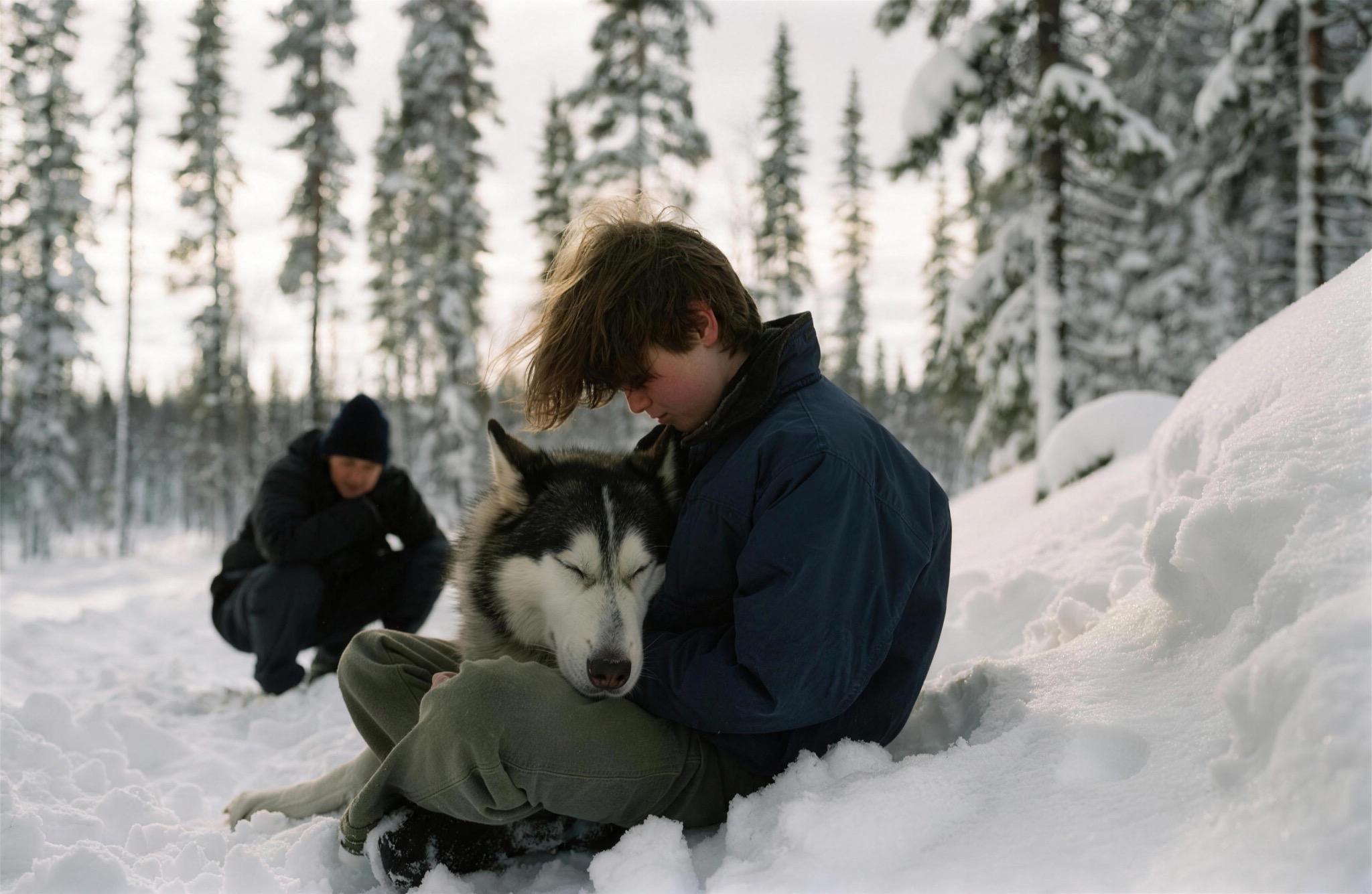A child nestled against a husky in the snow